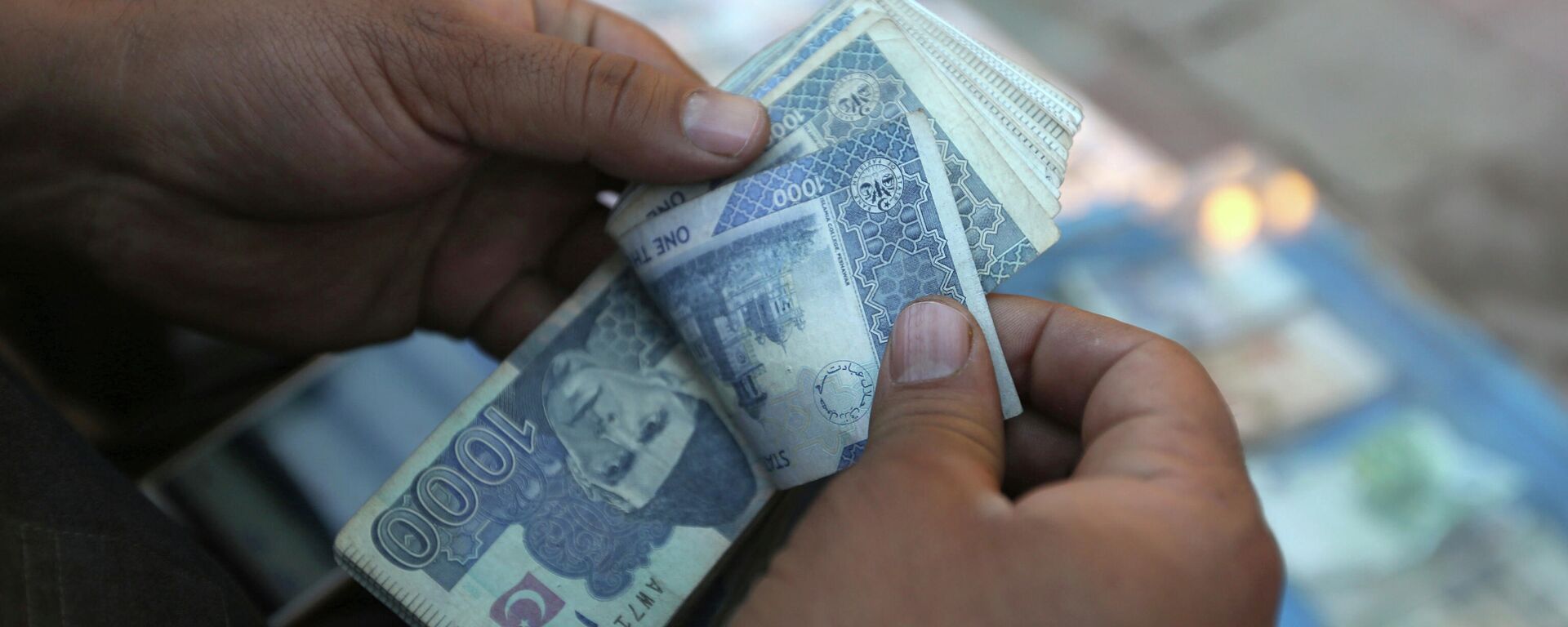 In this Monday, Dec. 5, 2016 photo, an Afghan money changer counts Pakistani currency banknotes at a money exchange market in Kabul, Afghanistan. Afghans are increasingly uncertain about their future, less confident in their government and more pessimistic than before on issues such as security, corruption, and rising unemployment, according to the annual survey by the San Francisco-based Asia Foundation released on Wednesday, Dec. 7, 2016. (AP Photo/Rahmat Gul) - Sputnik International, 1920, 26.06.2022