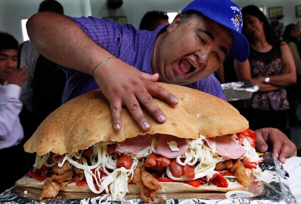 A man poses in front of a giant torta, or sandwich, during a press conference to promote the 13th annual Torta Festival, in Mexico City on  Wednesday, 20 July 2016. The five-day festival celebrates a range of Mexican street food made from the most exotic ingredients - including ostrich and stingray - to the classic ham, grilled steak or slow cooked pork. - Sputnik International