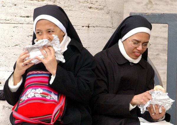 Two nuns eat their sandwiches during the Sunday Angelus, recited by Monsignor Leonardo Sandri at St Peter&#x27;s Square in the Vatican on 13 March 2005. They were there to see Pope John Paul II deliver his first live address since undergoing emergency surgery the month before. On 2 April, the monsignor announced to the world the death of the 84-year-old Pope. - Sputnik International
