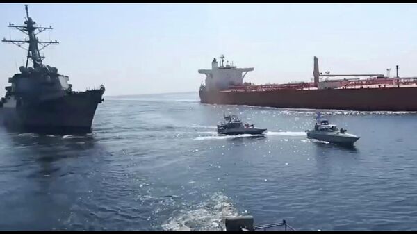 This frame grab from a video released by Iran's paramilitary Revolutionary Guard on Wednesday, Nov. 3, 2021, shows the Guard speed boats, center, in front of a U.S warship, left, amid the seizure of a Vietnamese-flagged oil tanker, right, in the Gulf of Oman. Iran seized the tanker in the Gulf of Oman last month and still holds the vessel, two U.S. officials told The Associated Press on Wednesday, revealing the latest provocation in Mideast waters as tensions escalate between Iran and the United States over Tehran's nuclear program. (Revolutionary Guard via AP) - Sputnik International