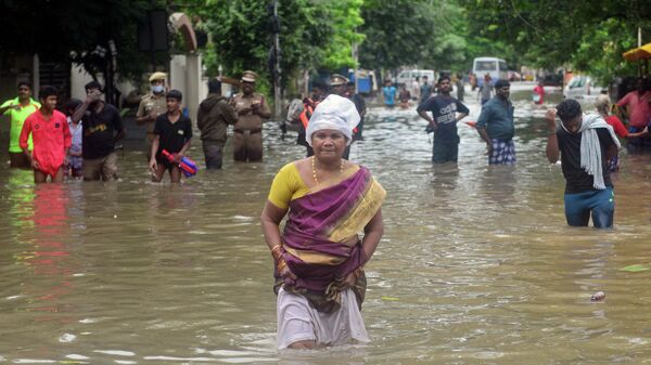 People wade through a flooded street after heavy rain shower in Chennai on November 7, 2021 - Sputnik International