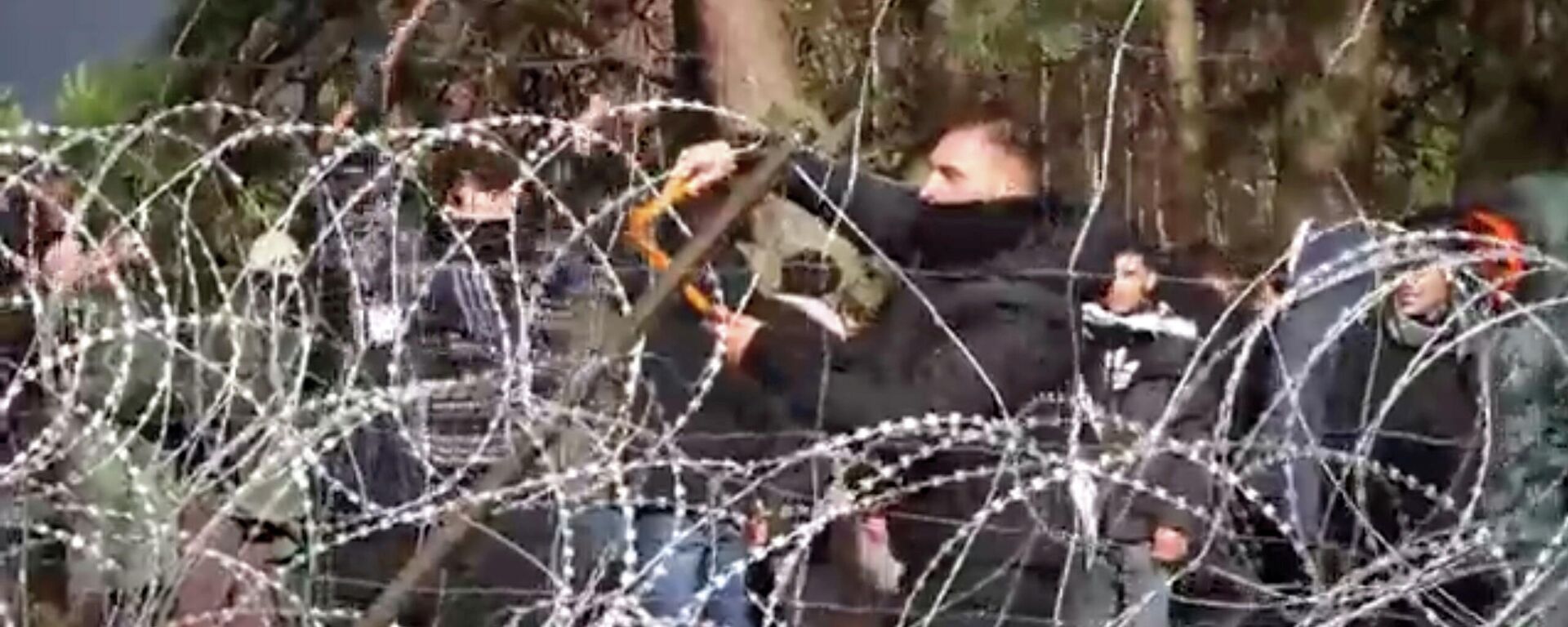 Migrants use wire cutters to cut the barbed wire as they try to cross the Belarus/Poland border near Kuznica Bialostocka, Poland, in this video-grab released by the Polish Defence Ministry, November 8, 2021 - Sputnik International, 1920, 09.11.2021