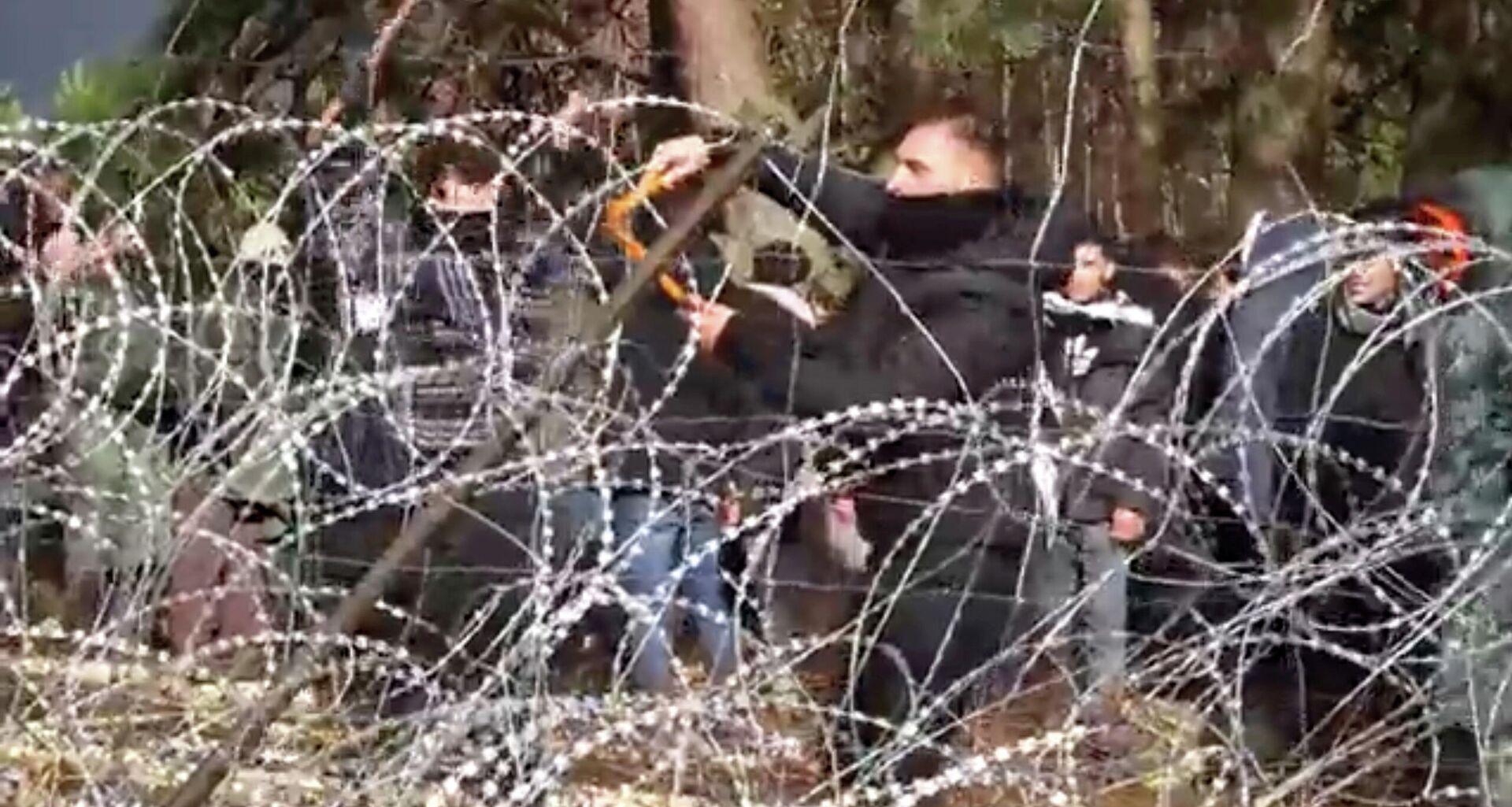 Migrants use wire cutters to cut the barbed wire as they try to cross the Belarus/Poland border near Kuznica Bialostocka, Poland, in this video-grab released by the Polish Defence Ministry, November 8, 2021 - Sputnik International, 1920, 10.11.2021