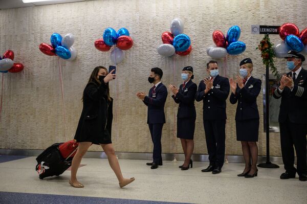 Passengers walk past airline staff as part of a welcoming event after arriving on a flight from the UK, following the easing of pandemic travel restrictions at JFK international airport in New York on 8 November 2021.  - Sputnik International
