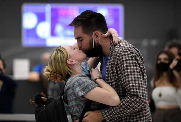A couple embrace each other as they are reunited upon her arrival on a flight from Frankfurt, Germany, as the US reopens air and land borders to vaccinated travellers for the first time since the Covid-19 restrictions were imposed, at Dulles International Airport in Chantilly, Virginia on 8 November 2021. - Sputnik International