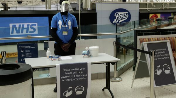 A member of staff stands ready to give out face masks and offer hand sanitiser to help stop the spread of coronavirus at Waterloo station in London, Thursday, June 4, 2020 - Sputnik International