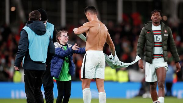Portugal's Cristiano Ronaldo gives his shirt to a young fan who walked on to the pitch at the end of the World Cup 2022 group A qualifying soccer match between the Republic of Ireland and Portugal at the Aviva stadium in Dublin, Thursday, Nov. 11, 2021 - Sputnik International