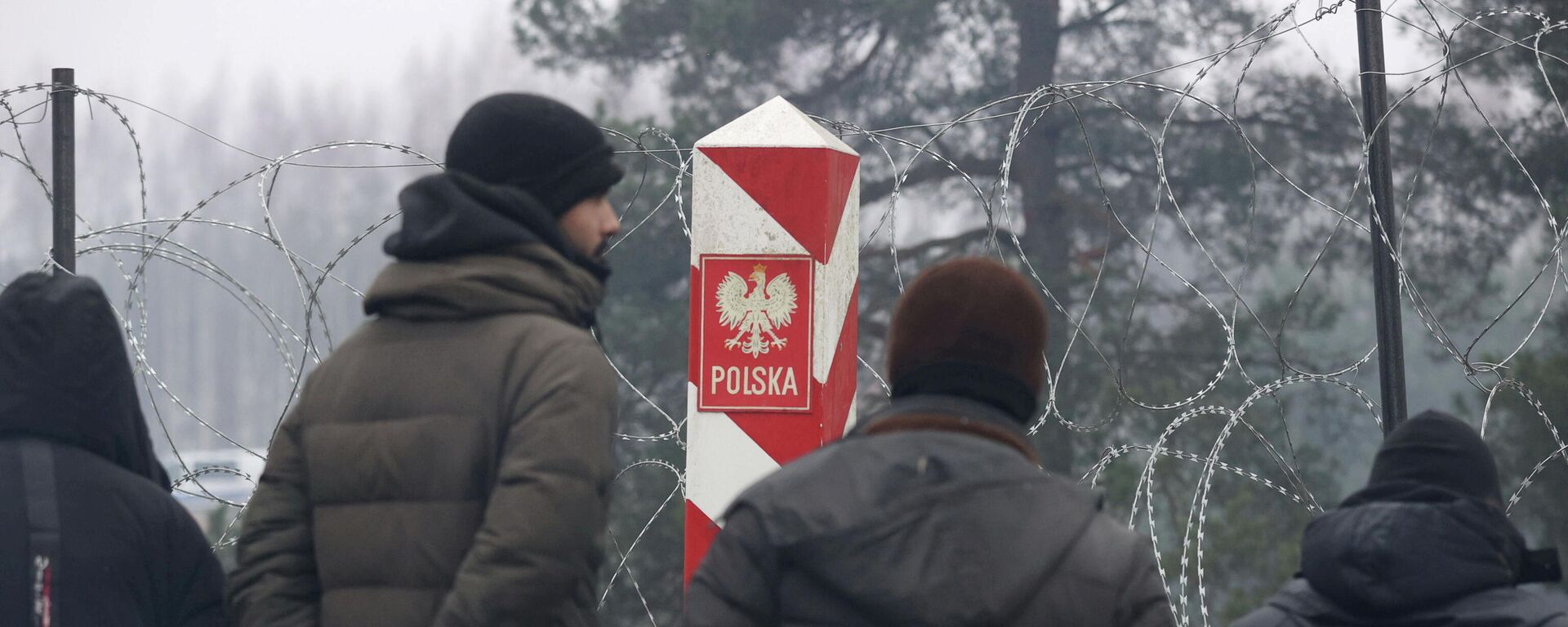 People gather near a barbed wire fence in a migrants' makeshift camp on the Belarusian-Polish border in the Grodno region, Belarus November 14, 2021 - Sputnik International, 1920, 15.11.2021
