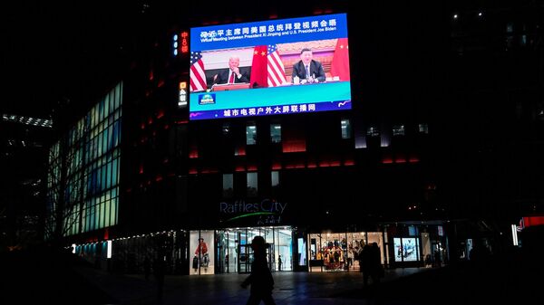 An outdoor screen shows a news program about a virtual meeting between Chinese President Xi Jinping and US President Joe Biden in Beijing on November 16, 2021. - Sputnik International