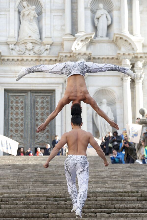Vietnamese artist Quoc Co Giang (down) and his brother Quoc Nghiep Giang try to break a Guinness World Record by climbing stairs with one carrying the other, balancing head to head, at the Cathedral of Girona on 22 December 2016. The Giang brothers broke the record with 90 stairs in 52 seconds. - Sputnik International