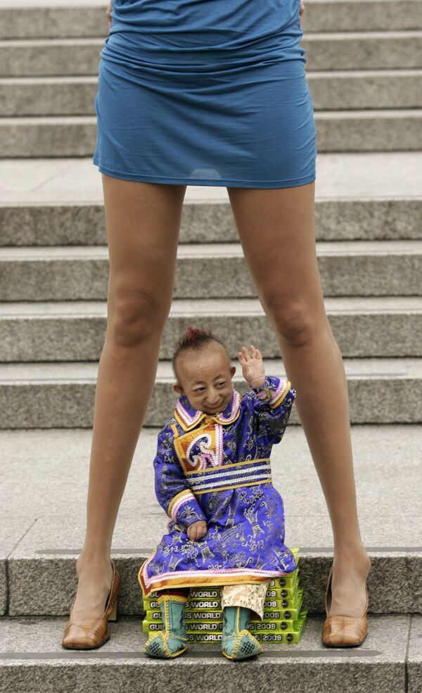 He Pingping from Inner Mongolia, in China&#x27;s autonomous region, the world&#x27;s smallest man, sits underneath Svetlana Pankratova from Russia, the Queen of Longest Legs, as they pose at Trafalgar Square in  London, Tuesday, 16 September 2008. Pingping, born with primordial dwarfism, holds the Guinness World Record for the smallest man at 74.61 cm (2 feet and 5.37 inches) and Pankratova holds the Guinness World Record for the longest legs of any woman at 132 cm (4 feet 4 inches) in length. - Sputnik International
