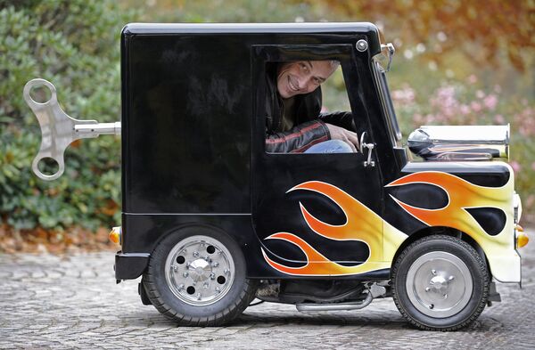 British constructor Perry Watkins sits in his &quot;Wind Up&quot; mini car on a street in Essen, Germany, Monday, 8 November 2010. The car is listed in the Guinness book of records as the world&#x27;s smallest car with a license to drive on public streets. Measuring just 41 inches high, 51 inches long and only 26 inches wide, the mini always finds a parking space. It can drive 60 kph and even has security belts. The car will be shown at the motor show starting Nov. 27 in Essen. - Sputnik International