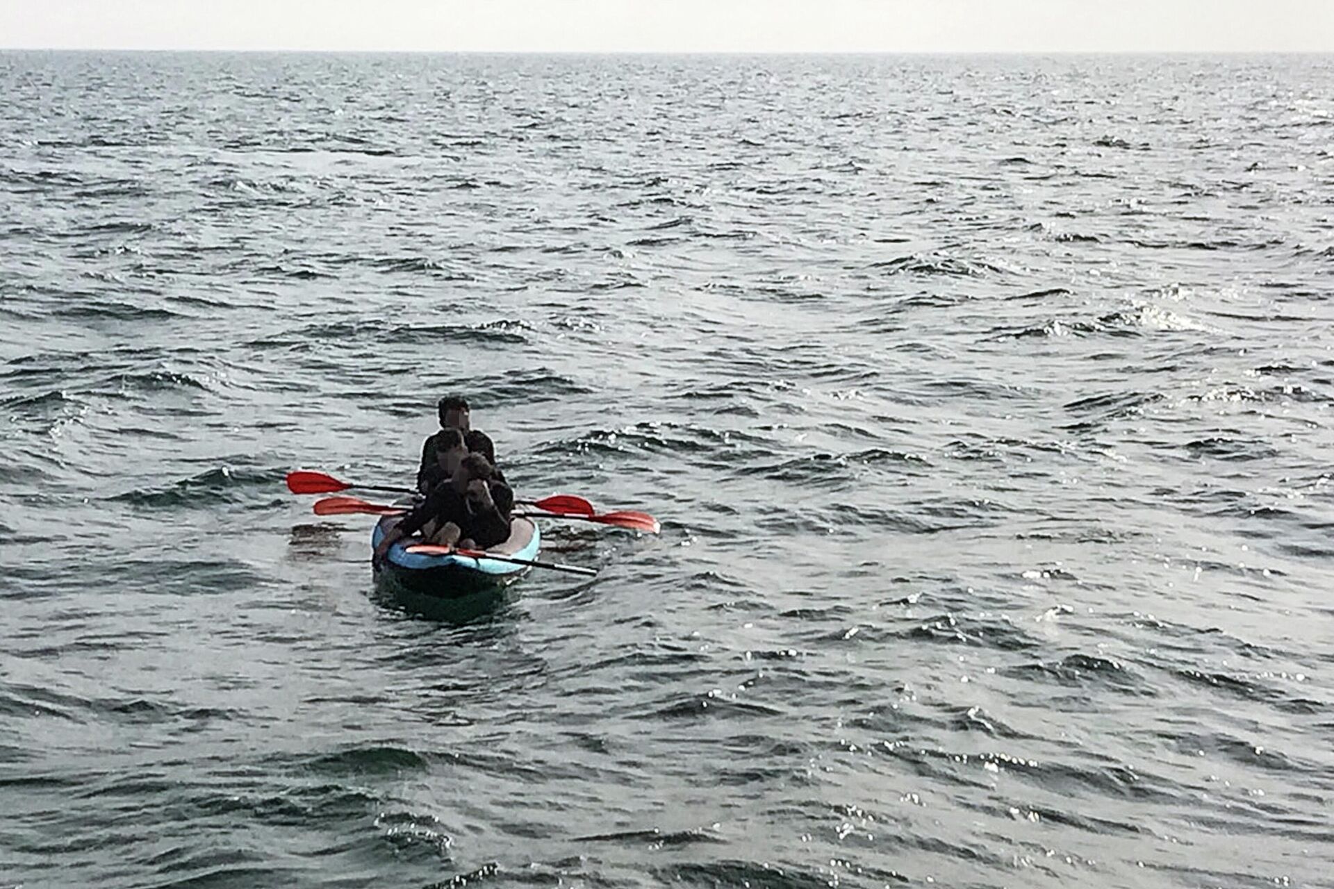 Three migrants who were attempting to cross The English Channel from France to Britain are seen as they drift in an inflatable canoe off the French coast at Calais on August 4, 2018, before being rescued by lifeguards of Les Sauveteurs en Mer (SNSM) - Sputnik International, 1920, 03.12.2021