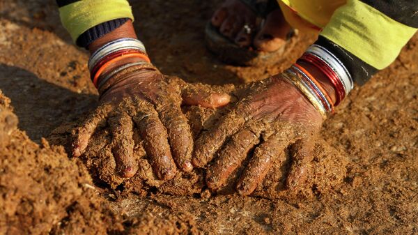 An Indian village woman makes cow dung cakes in Allahabad, India, Wednesday, Dec. 22, 2010 - Sputnik International