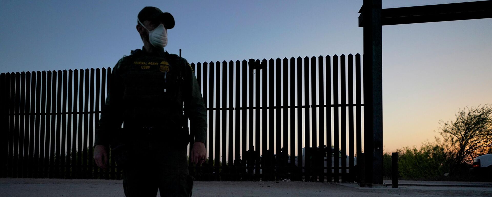 In this March 21, 2021 file photo, a U.S. Customs and Border Protection agent looks on near a gate on the U.S.-Mexico border wall as agents take migrants into custody, in Abram-Perezville, Texas. - Sputnik International, 1920, 26.02.2022