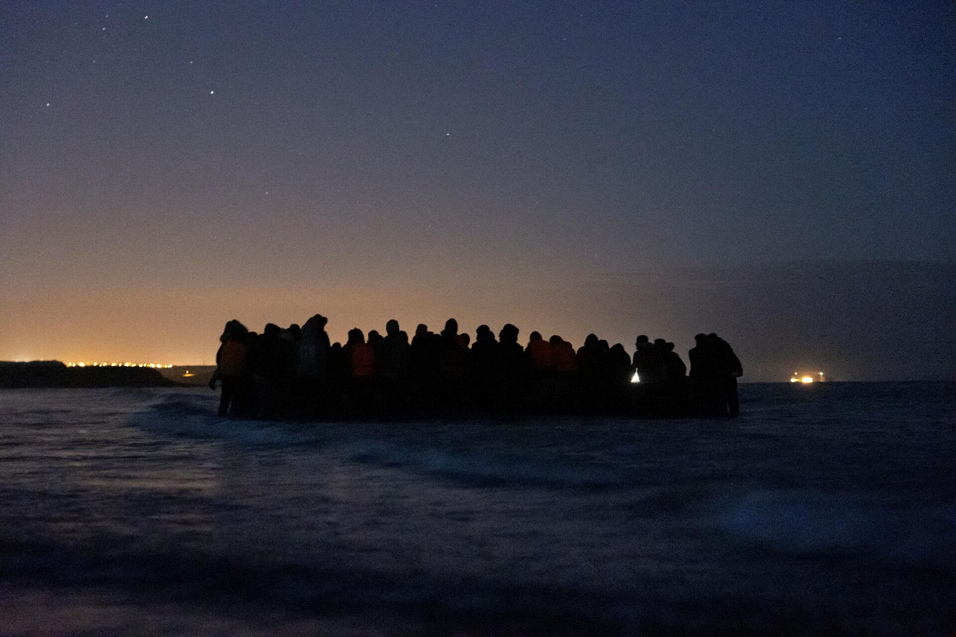 A group of 80 migrants get on one of the inflatable boats to cross the Channel towards England at night, near Wimereux, northern France, on October 16, 2021 - Sputnik International, 1920, 22.11.2021