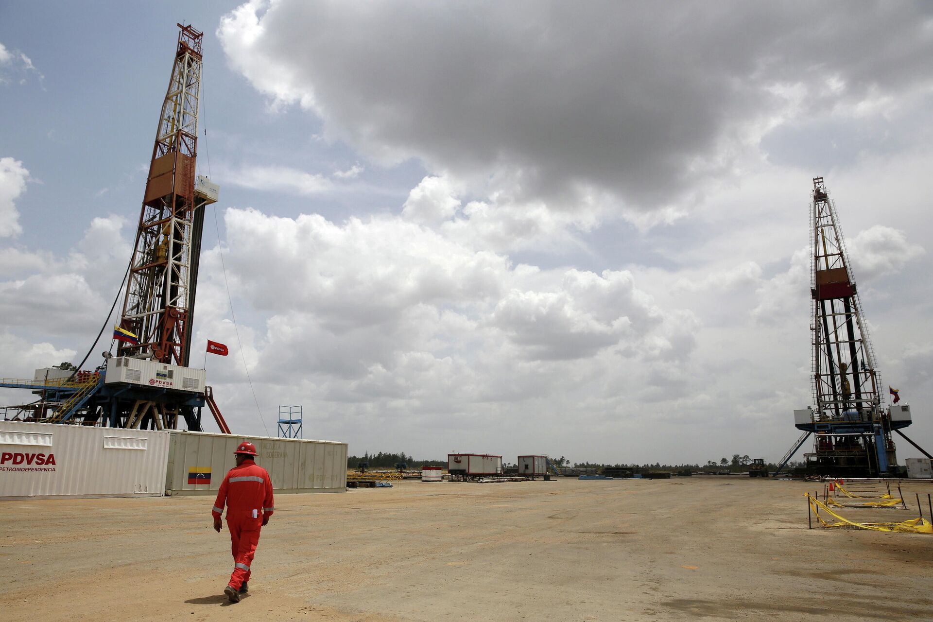 An oilfield worker walks next to drilling rigs at an oil well operated by Venezuela's state oil company PDVSA, in the oil rich Orinoco belt, April 16, 2015 - Sputnik International, 1920, 19.11.2021