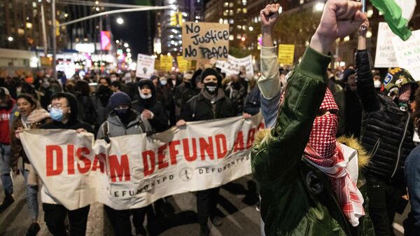 Demonstrators raise their fists while marching on the street during a protest against the Kyle Rittenhouse not-guilty verdict near the Barclays Center in New York on November 19, 2021 - Sputnik International