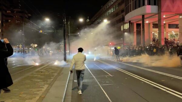 Protesters watch smoke flares on as street in Rotterdam, Netherlands November 20, 2021, in this screen grab obtained from a social media video. Video recorded November 20, 2021. Sven Simcic - Video In Verzet via REUTERS THIS IMAGE HAS BEEN SUPPLIED BY A THIRD PARTY. MANDATORY CREDIT. NO RESALES. NO ARCHIVES. - Sputnik International
