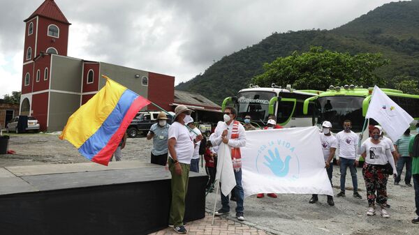 Former rebel commanders and current members of the FARC political party, Pastor Alape, second from left, and Rodrigo Granda, far left with Colombian flag, arrive for a ceremony to apologize to locals for the kidnappings carried out by the FARC over decades in the rural area of Pipiral near Villavicencio, Colombia, Thursday, Oct. 29, 2020. Ex-combatants and social organizations plan to march to Bogota this weekend to demand the government guarantee their right to life and compliance with the 2016 peace agreement, amid hundreds of subsequent ex-rebel deaths. - Sputnik International