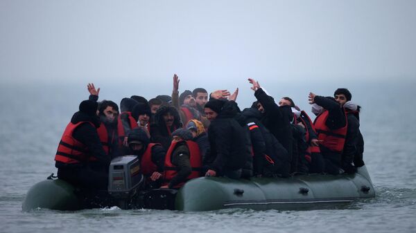 A group of more than 40 migrants react as they succeeded to get on an inflatable dinghy, to leave the coast of northern France and to cross the English Channel, near Wimereux, France, November 24, 2021. - Sputnik International