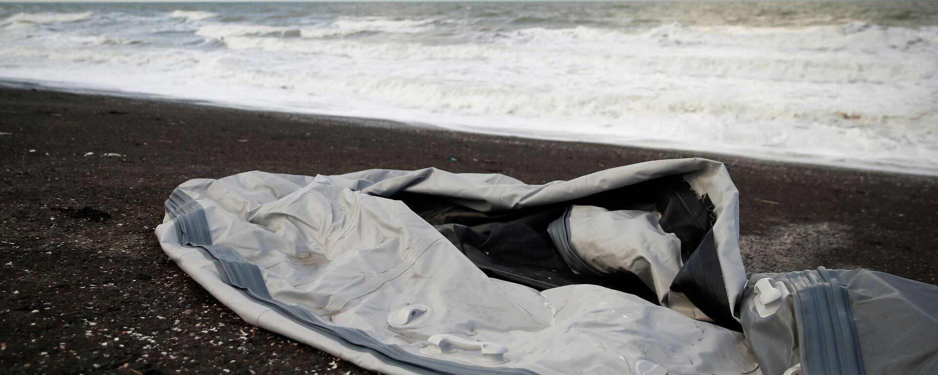 A damaged inflatable dinghy is seen on Loon Beach, the day after 27 migrants died when their dinghy deflated as they attempted to cross the English Channel, in Dunkerque near Calais, France, November 25, 2021.  - Sputnik International, 1920, 25.11.2021