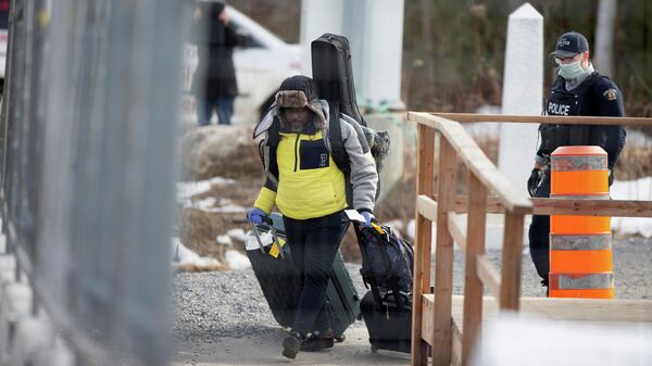 An asylum seeker crosses the border from New York into Canada followed by a Royal Canadian Mounted Police (RCMP) officer at Roxham Road in Hemmingford, Quebec, Canada (File) - Sputnik International