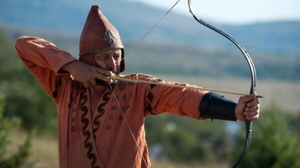 Participant of the Scolotoi Nomad Camp reenactment shoots a bow at the Crimean military historical festival in Pervomaika, Balaklava District - Sputnik International
