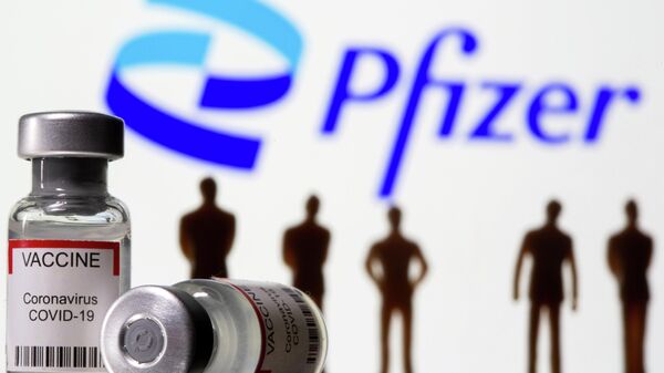 Syringe and vial labelled coronavirus disease (COVID-19) vaccine and small toy figures are seen front of displayed new Pfizer logo in this illustration taken, June 24, 2021. - Sputnik International