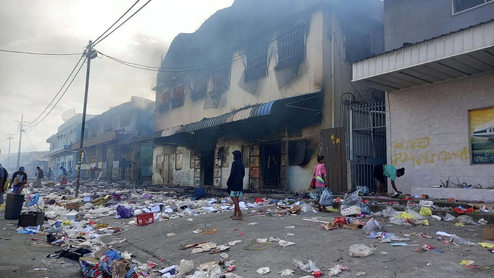 People stand amid debris in front of a burned-out building after days of unrest in Honiara, Solomon Islands November 26, 2021. - Sputnik International, 1920, 27.11.2021