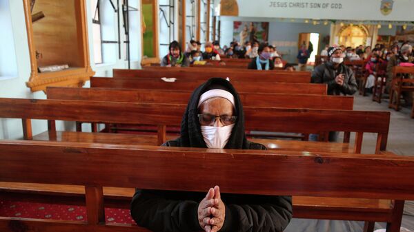 An Indian Christian wearing a face mask as a precaution against the coronavirus prays at Saint Mary's Cathedral on Christmas in Jammu, India, Friday, Dec. 25, 2020 - Sputnik International