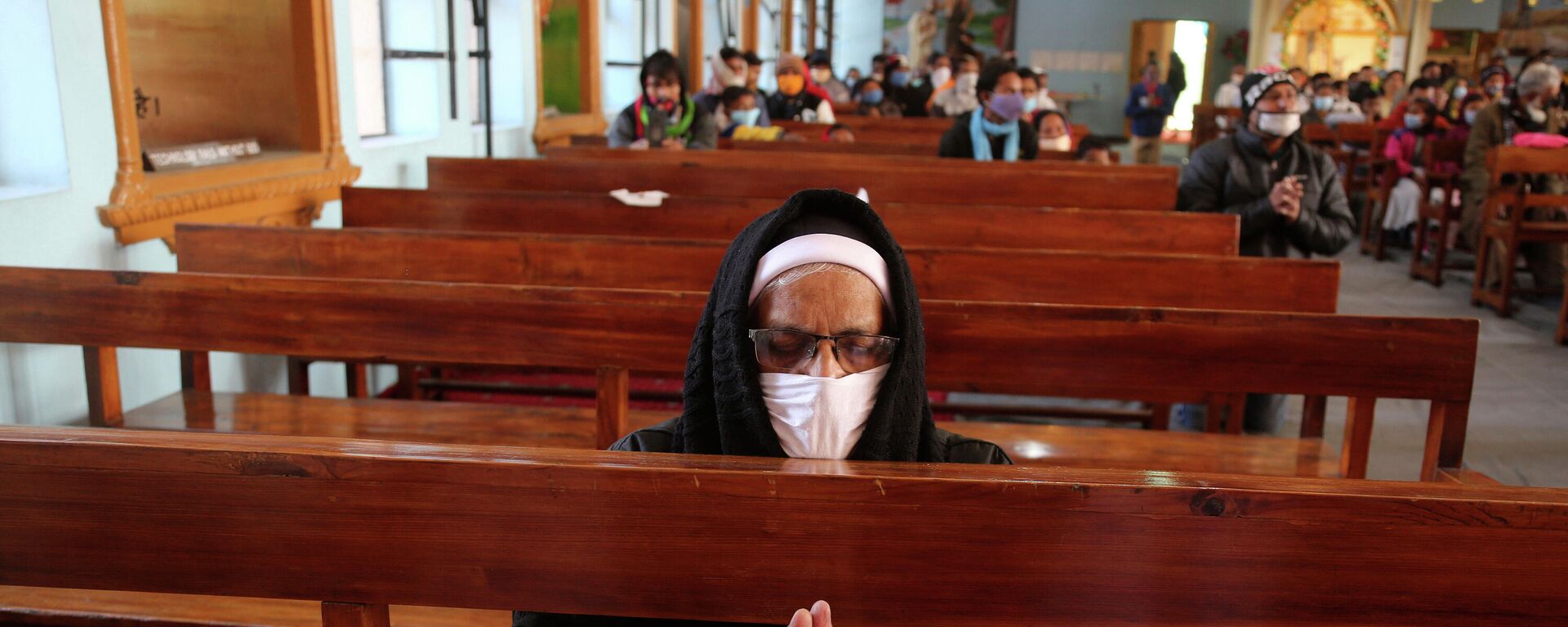 An Indian Christian wearing a face mask as a precaution against the coronavirus prays at Saint Mary's Cathedral on Christmas in Jammu, India, Friday, Dec. 25, 2020 - Sputnik International, 1920, 29.11.2021