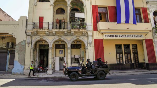 Special forces police patrol the streets as they drive past a large Cuban flag hanging from the facade of a building, in Havana, Cuba, Wednesday, July 21, 2021. - Sputnik International