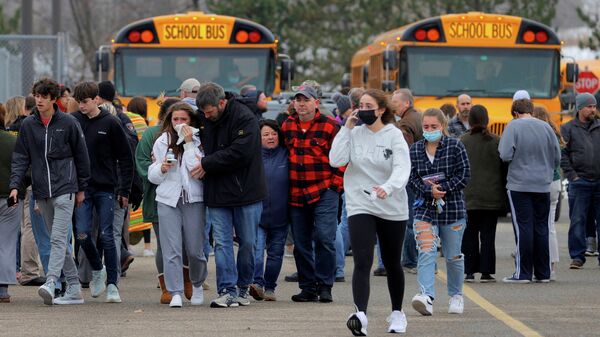 Parents walk away with their kids from the Meijer's parking lot where many students gathered following an active shooter situation at Oxford High School in Oxford, Michigan, U.S. November 30, 2021 - Sputnik International