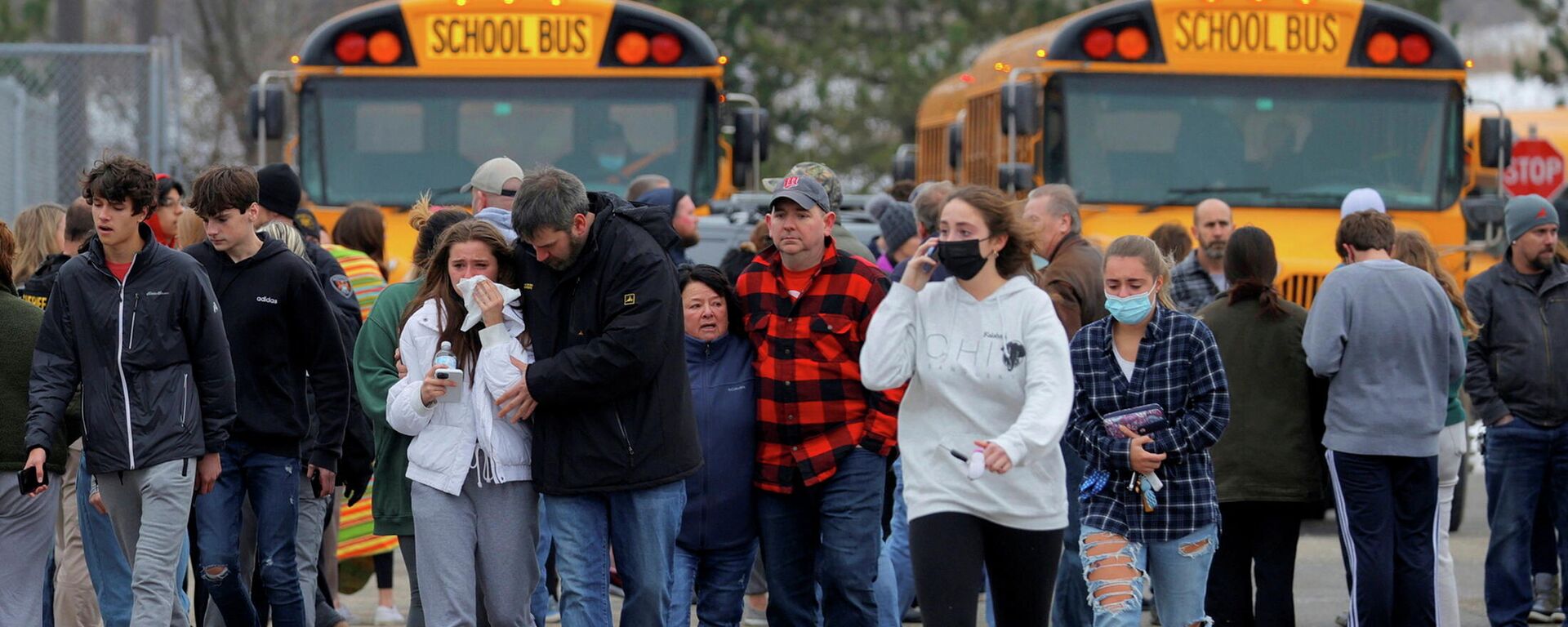 Parents walk away with their kids from the Meijer's parking lot where many students gathered following an active shooter situation at Oxford High School in Oxford, Michigan, U.S. November 30, 2021 - Sputnik International, 1920, 01.12.2021