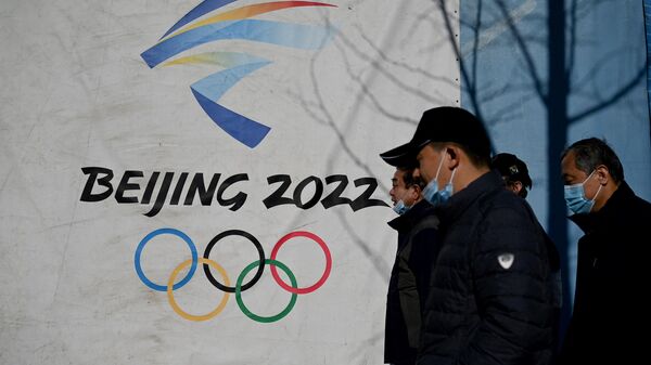 People walk past the Beijing 2022 Winter Olympics logo at the Shougang Park in Beijing on December 1, 2021 - Sputnik International