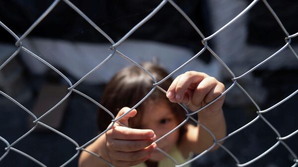 A girl plays with a fence inside a migrant camp near the El Chaparral border crossing in Tijuana, Mexico November 8, 2021. Picture taken on November 8, 2021. - Sputnik International