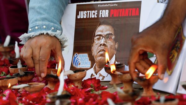 People light oil lamps next to laid roses to express their condolences to the people of Sri Lanka, following the lynching of the Sri Lankan manager of a garment factory after an attack on the factory in Sialkot, in Karachi, Pakistan December 5, 2021 - Sputnik International