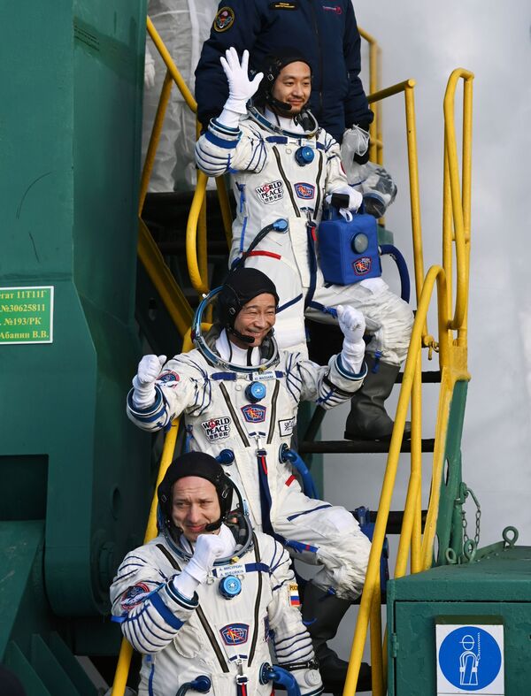 Roscosmos cosmonaut Alexander Misurkin (first from below) and space tourists, Japanese entrepreneur Yusaku Maezawa and his production assistant Yozo Hirano, wave to well-wishers before the launch of the Soyuz-2.1 rocket with the Soyuz MS-20 spacecraft to the International Space Station.  - Sputnik International