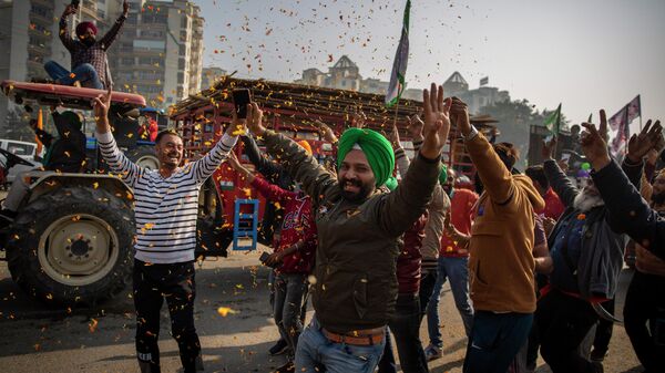 Indian farmers are showered with flower petals as they dance while leaving the protest site in Singhu, on the outskirts of New Delhi, India, Saturday, Dec. 11, 2021.  - Sputnik International