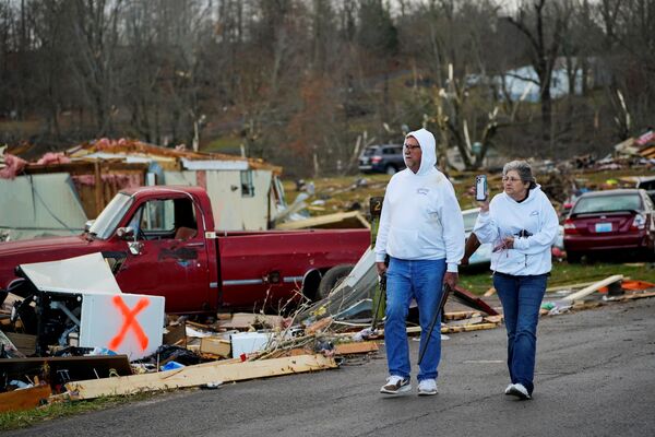 Bill Mosley walks with his wife Bonnie while carrying two of his guns, the only items he was able to recover after their home was destroyed, as a devastating outbreak of tornadoes ripped through several states. Earlington, Kentucky, on 11 December 2021. - Sputnik International