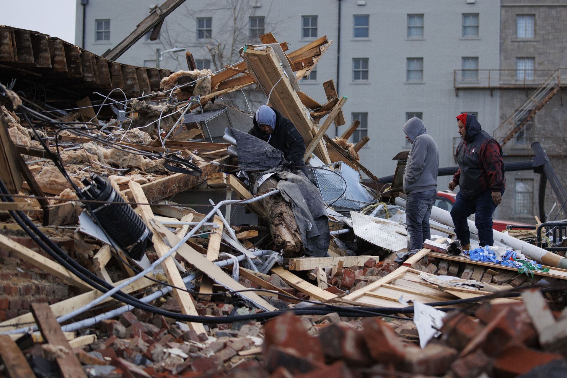 People search through a tornado-damaged building on 11 December 2021 in Mayfield, Kentucky. Multiple tornadoes tore through parts of the lower Midwest late on Friday night leaving a large path of destruction and unknown fatalities.   - Sputnik International, 1920, 14.12.2021