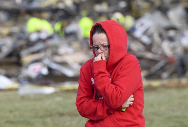 A woman walks away from what is left of the Mayfield Consumer Products Candle Factory as emergency workers comb the rubble after it was destroyed by a tornado in Mayfield, Kentucky, on 11 December 2021. - Sputnik International