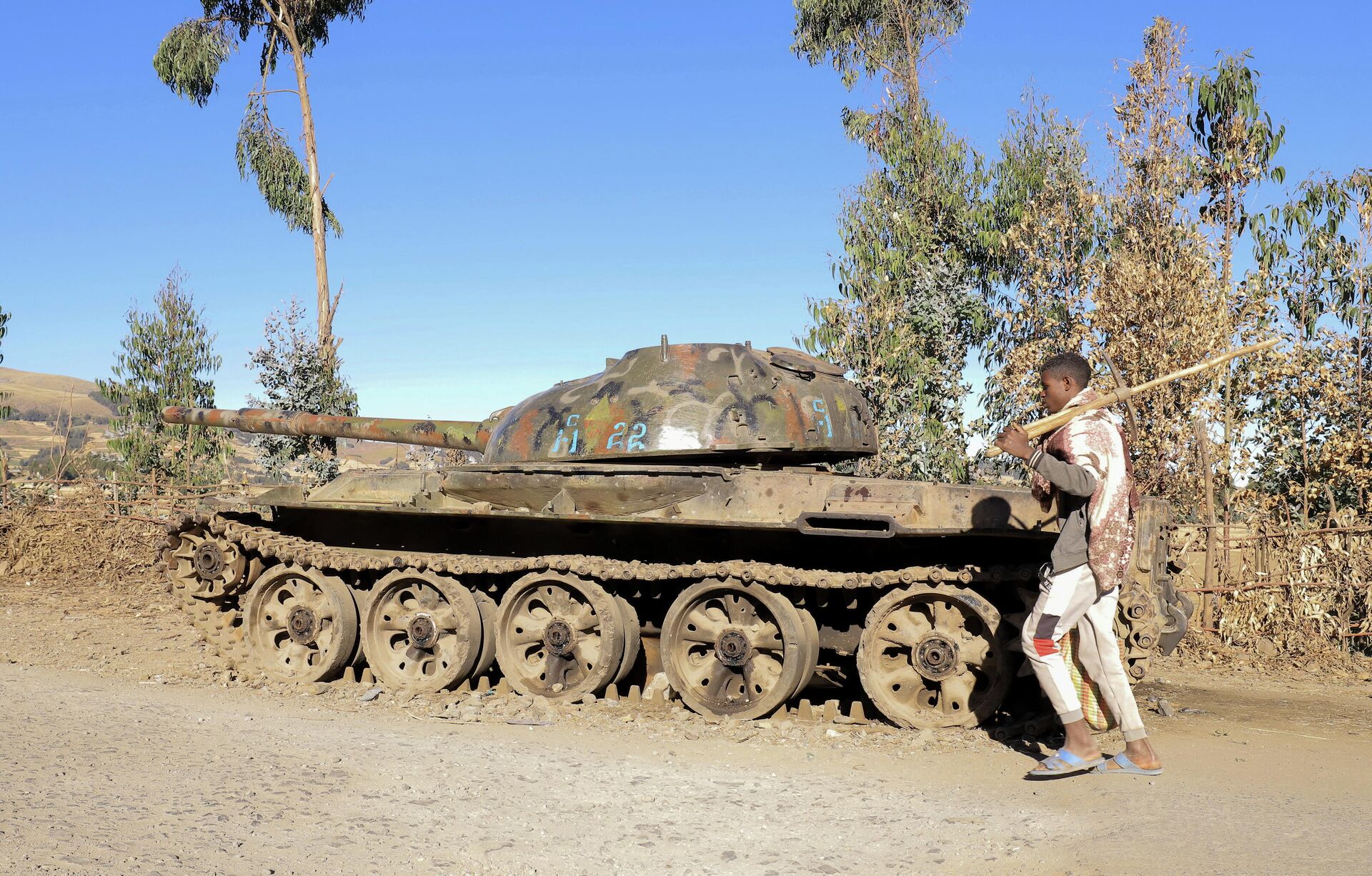 A  farmer walks past a military tank destroyed recently during fighting between the Ethiopian National Defense Force (ENDF) and the Tigray People's Liberation Front (TPLF) in Damot Kebele of Amhara region, Ethiopia December 7, 2021. Picture taken December 7, 2021. - Sputnik International, 1920, 14.12.2021