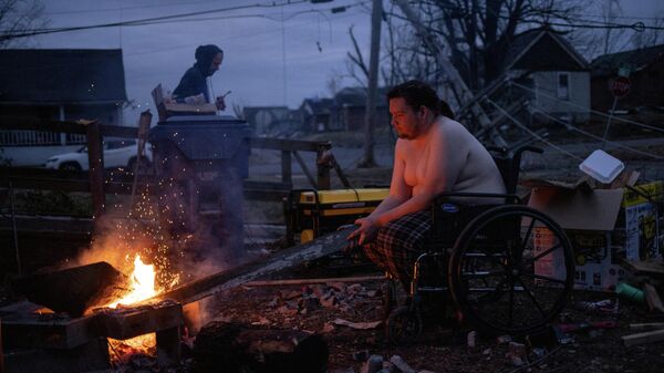 Jeffrey Bowlin keeps warm next to a wood fire in his front yard after his neighborhood lost power in the aftermath of a tornado in Mayfield, Kentucky, U.S. December 14, 2021 - Sputnik International