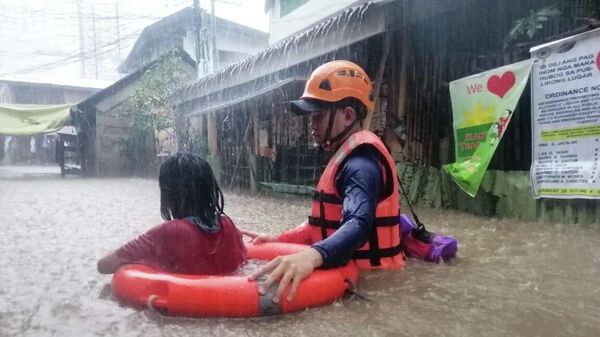 A Philippine Coast Guard personnel assists a resident in their evacuation due to flooding caused by Typhoon Rai in Cagayan De Oro City, Philippines, December 16, 2021 - Sputnik International
