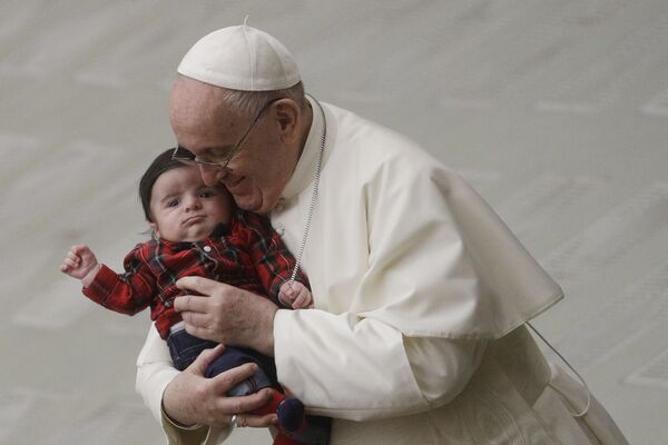 In this December 21, 2020 file photo, Pope Francis cuddles a baby as he exchanges holiday greetings with Vatican employees in the Paul VI hall. - Sputnik International