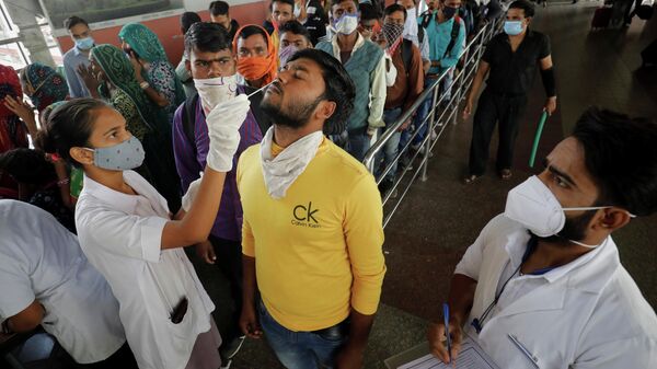 A healthcare worker collects a swab sample from a passenger as others wait for their turn upon arrival at a railway station during a rapid antigen testing drive for the coronavirus disease (COVID-19) in Ahmedabad, India, November 30, 2021.  - Sputnik International