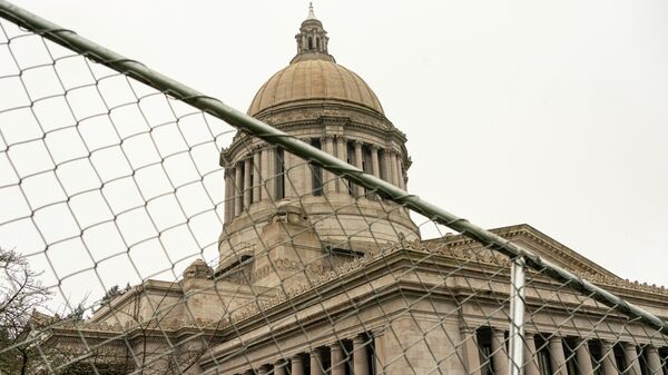 The Washington State Capitol is seen behind protective fencing on January 20, 2021 in Olympia, United States. One Donald Trump supporter held a sign at an otherwise quiet capitol campus on Presidential Inauguration Day today.   - Sputnik International