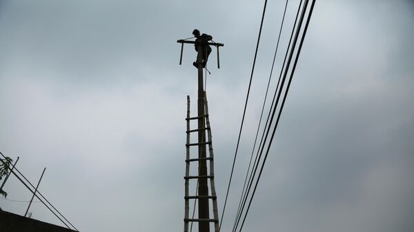 An Indian electricity department worker climbs on a pole to fix power lines as monsoon clouds gather above in Jammu, India, Sunday, July 18, 2021 - Sputnik International